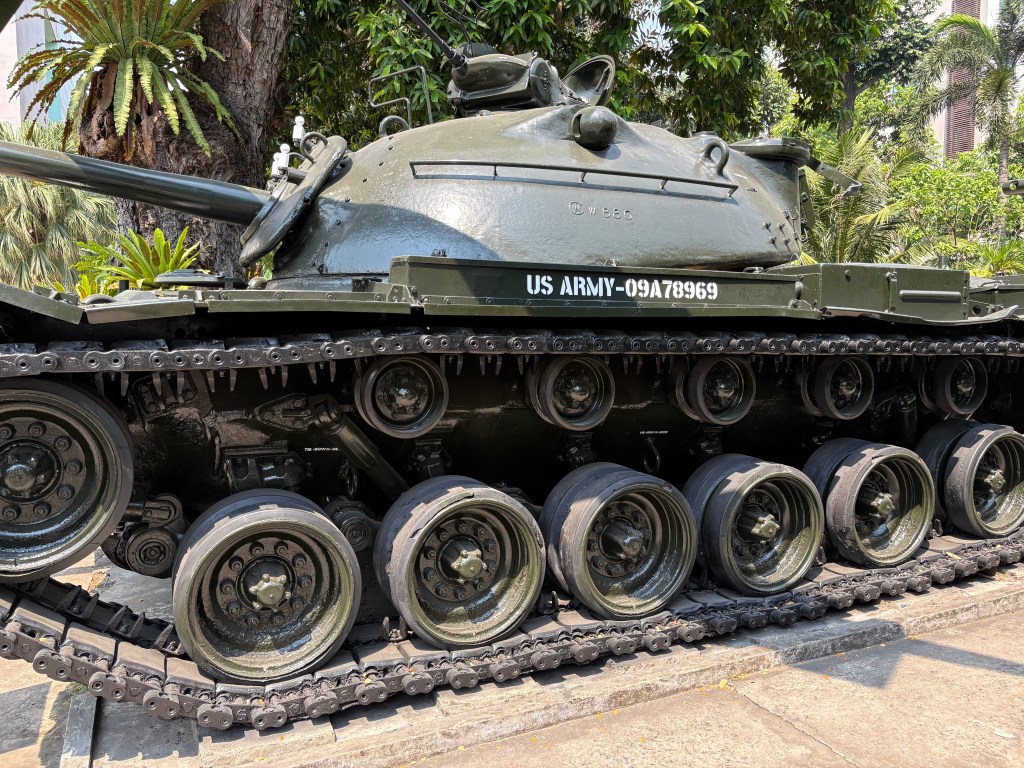 Close-up view of a military tank with visible tracks and wheels, featuring green paint and markings identifying it as part of the US Army.