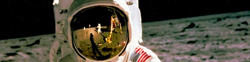 An astronaut in a spacesuit standing on the lunar surface, with a reflection of the moon lander visible in the helmet visor.
