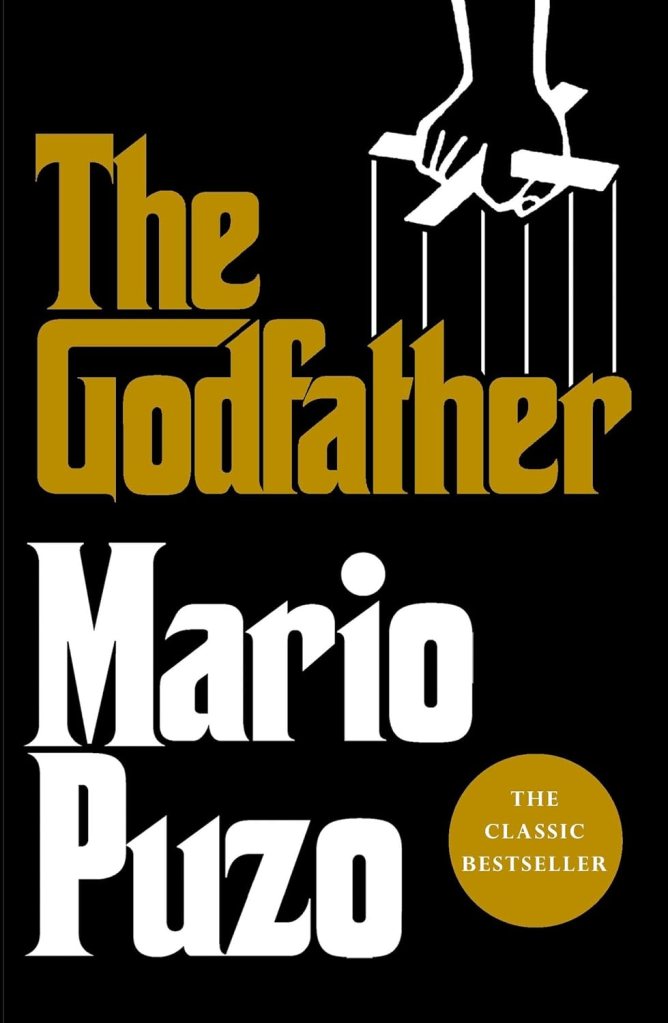 Cover of 'The Godfather' by Mario Puzo, featuring a puppet hand controlling marionette strings, with bold white and gold typography on a black background.