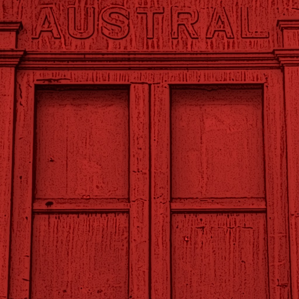 Close-up of a red wall featuring the word 'AUSTRAL' engraved above two rectangular panels.