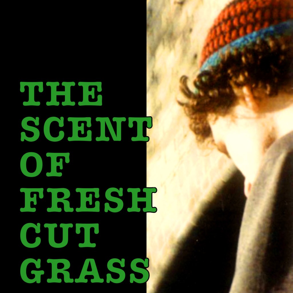 A close-up image of a person's head and shoulder with curly hair, wearing a red and blue striped beanie, against a blurred background. The text 'THE SCENT OF FRESH CUT GRASS' is displayed prominently in green on the left side.